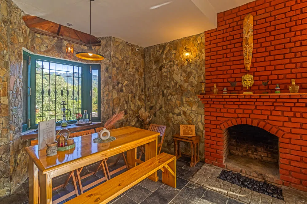 Drawing and dining room with brick fireplace in the Mukteshwar villa