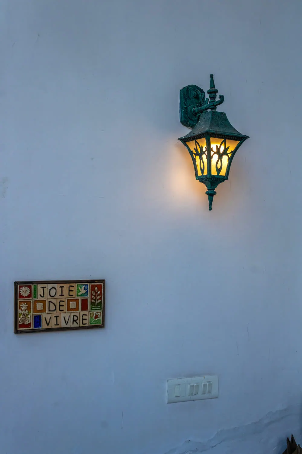 Hand-painted Joie de Vivre tile sign and iron lantern at the villa entrance